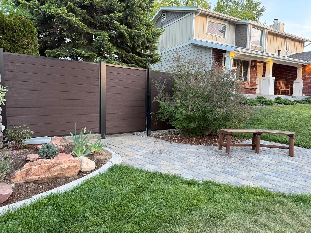 Composite privacy fence beside a paver path and planting bed in a front yard