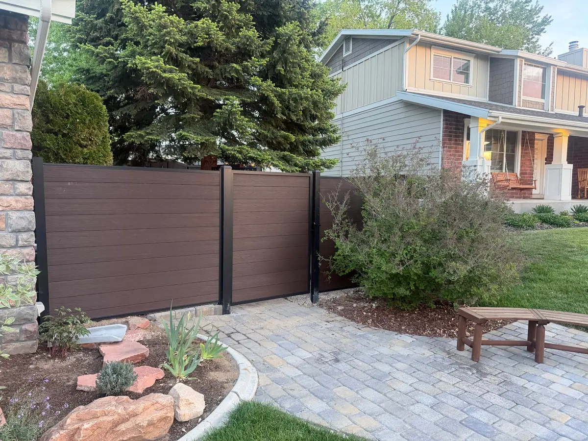 Composite fence and paver patio beside a landscaped bed