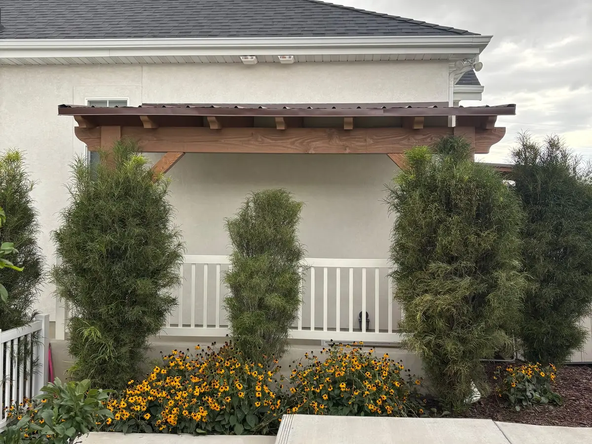 Two-story home with a cedar pergola over the entry and evergreen plantings