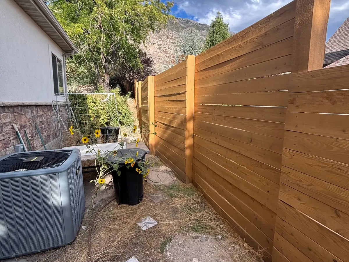 Horizontal cedar fence beside a stone wall and flowers
