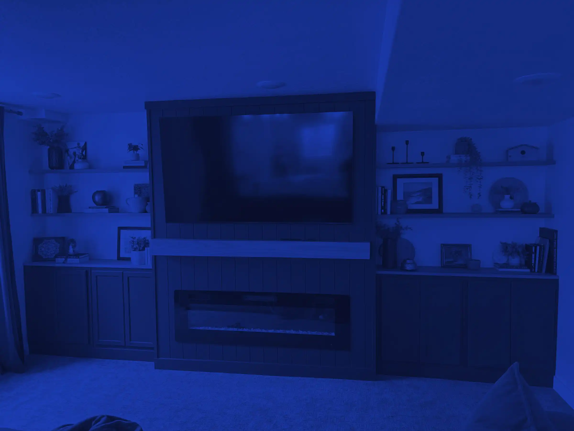 Built-in media wall with a linear fireplace, shelving, and cabinetry in a finished basement