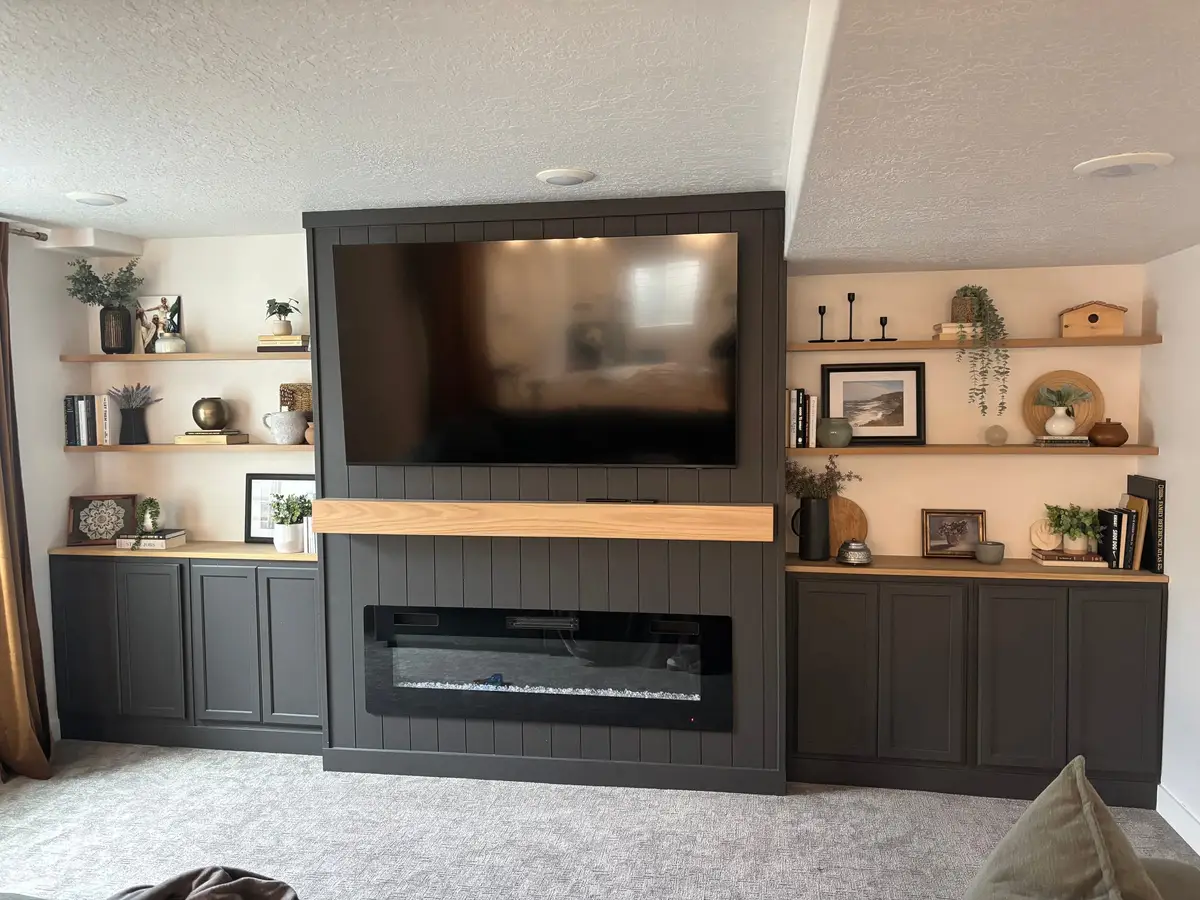 Built-in media wall with a linear fireplace, shelving, and cabinetry in a finished basement