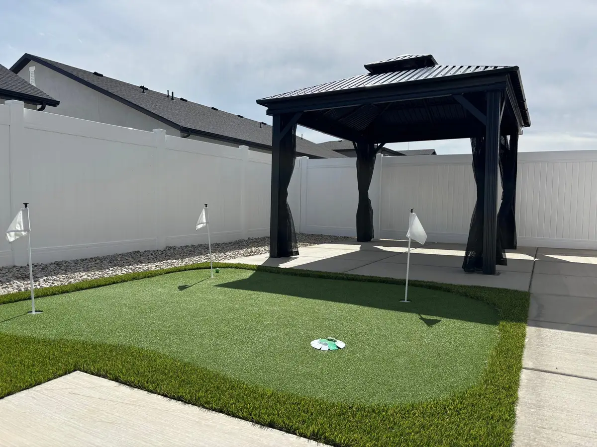 Backyard putting green beside a black steel gazebo